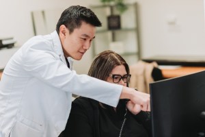 The doctor with a female staff, pointing at the computer monitor